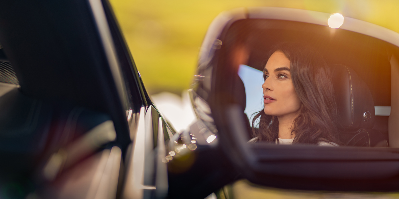 Bentley Firenze profile of dark haired woman's face in mirror of Bentley car in sunlight