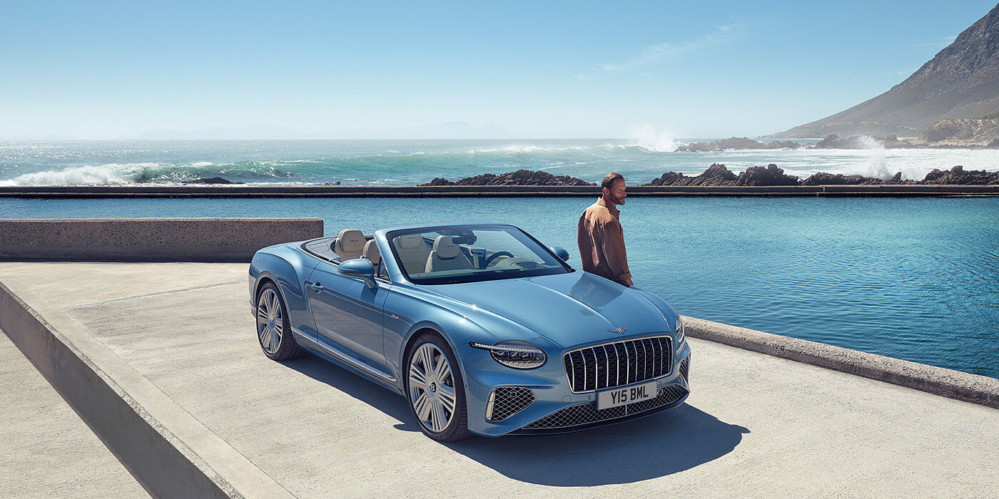 Bentley Firenze New Bentley Continental GTC Azure convertible front view in Light Windsor blue paint with 22 inch ten spoke wheels parked by the sea in the sunshine