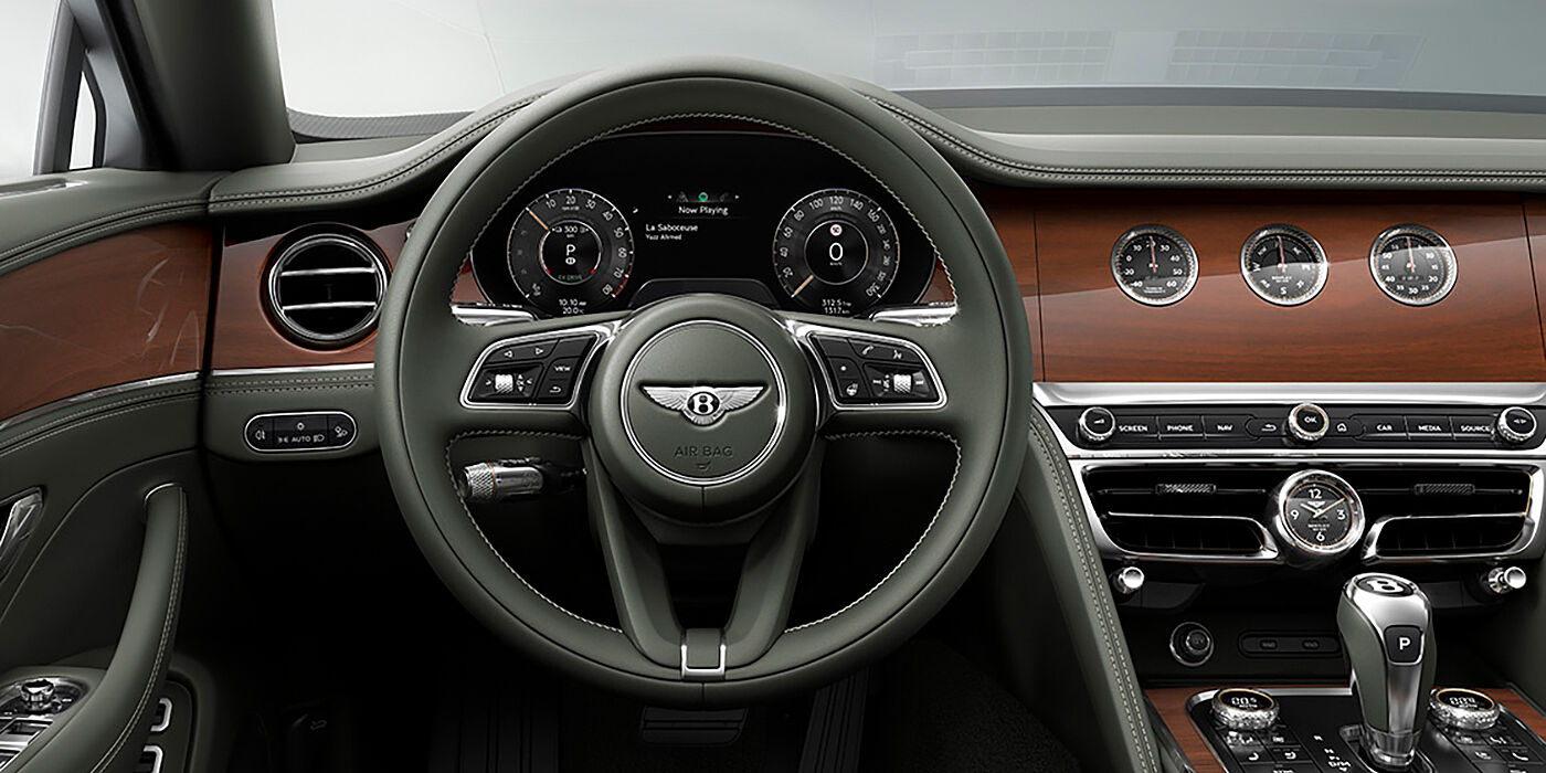 Bentley Firenze New Bentley Flying Spur sedan front cabin in Cumbrian Green hide and Crown Cut walnut veneer showing steering wheel and Rotating Display with three clocks on face