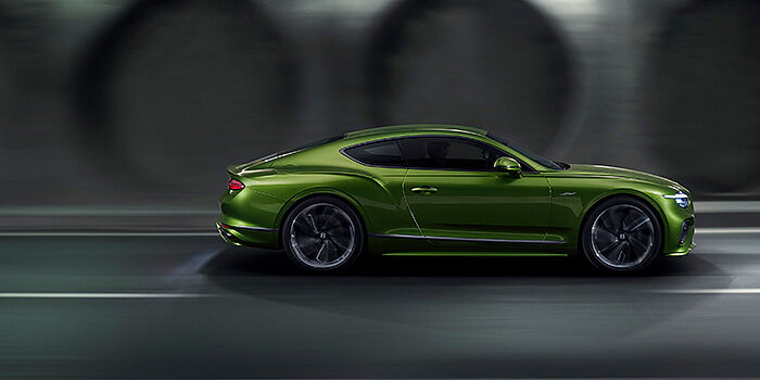  Bentley Firenze Bentley Continental GT coupe in Tourmaline Green paint driving in profile on a dark road