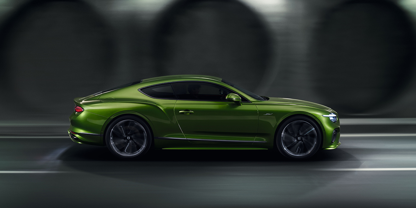 Bentley Firenze Bentley Continental GT coupe in Tourmaline Green paint driving in profile on a dark road